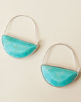In front of a cream background is a pair of silver hoops. The bottom half of the hoop is a turquoise stone.