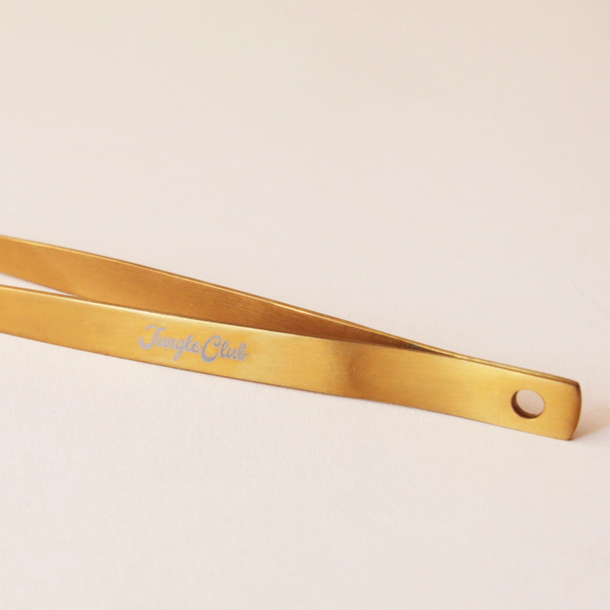 Brass tweezers with a slim design and a pointed tip perfect for handling spiky cacti. On the side of the tweezer there is text that reads, &quot;Jungle Club&quot; I white cursive.