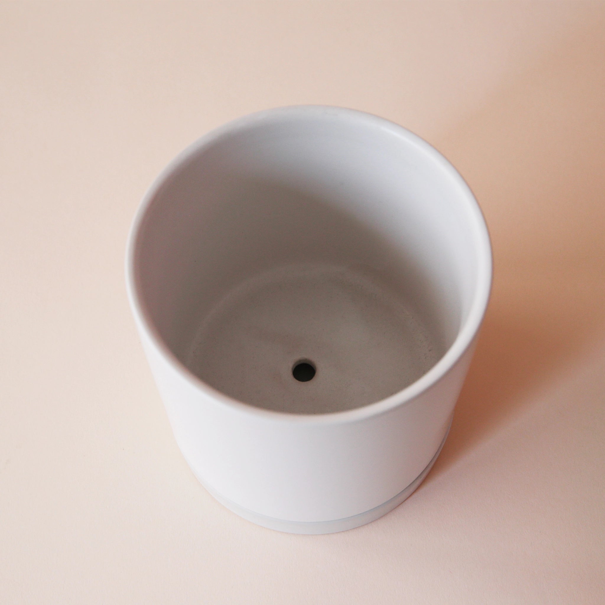 interior view of a simple white pot with drainage hole