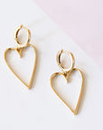 A pair of gold hoop earrings with a larger hold heart shape hoop attached to that.