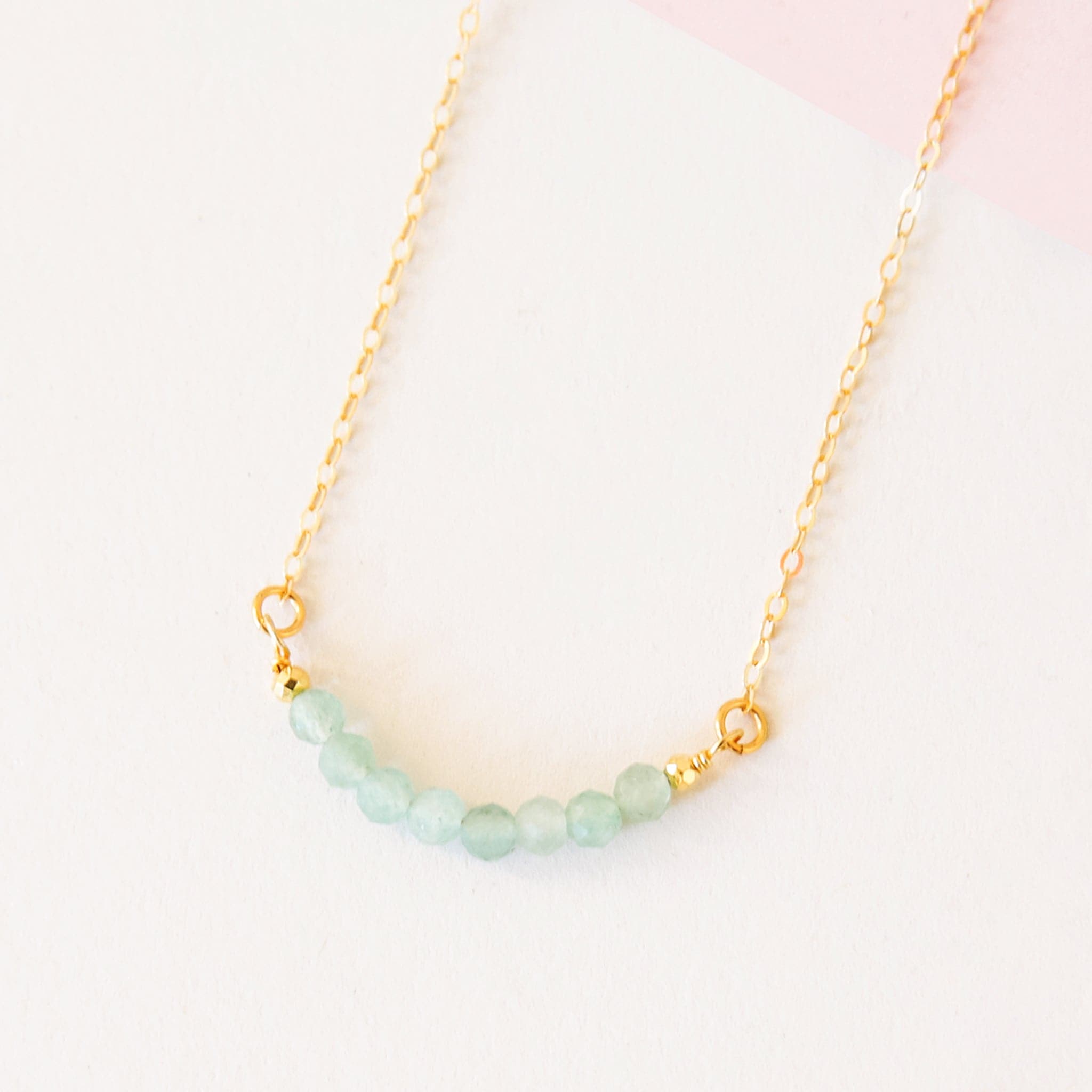 Eight amazonite beads lined up on a gold chain.