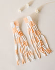 Beaded peach and white earrings with a checker design. They have long dangling beaded strings that make for a fun addition to any outfit.