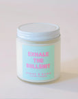 Clear, glass jar candle with white metal lid. Label says "Exhale the bullshit" in pink with a aqua colored background.