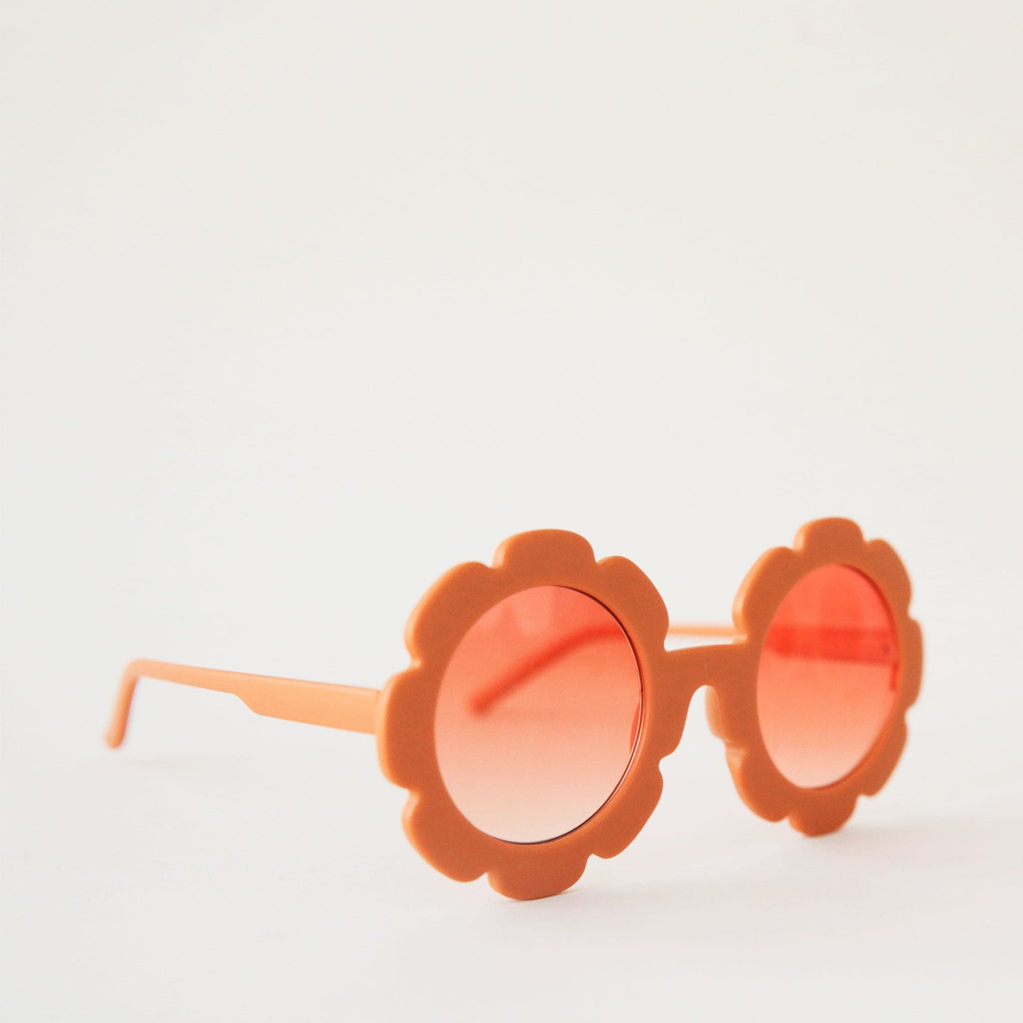 An orange flower shaped sunglass with a round orange lens in the center.