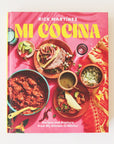 A bright pink book cover with a yellow font title that reads, "Mi Cocina" along with an assortment of Mexican cuisine.