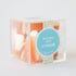 A clear acrylic box with peaches and cream candies inside. They look like small orange slices with a white bottom.
