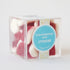 A clear acrylic box with strawberries and cream candies inside. They look like small strawberry slices with a white bottom.