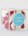 A clear acrylic box with strawberries and cream candies inside. They look like small strawberry slices with a white bottom.