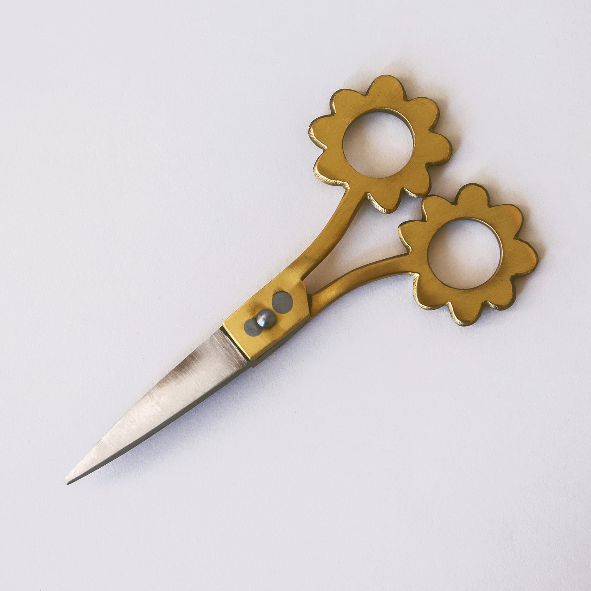 These scissors have stainless steel blades and brass handles. The holes to place your fingers through are in the shape of flowers.