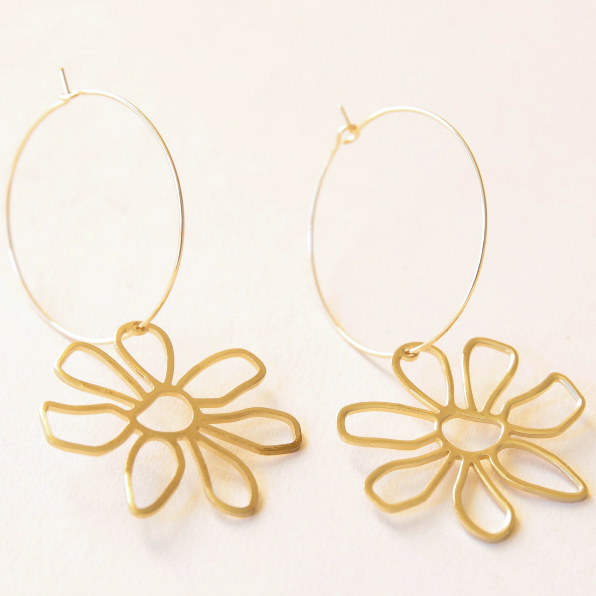 A thin gold hoop earring with a line flower charm.