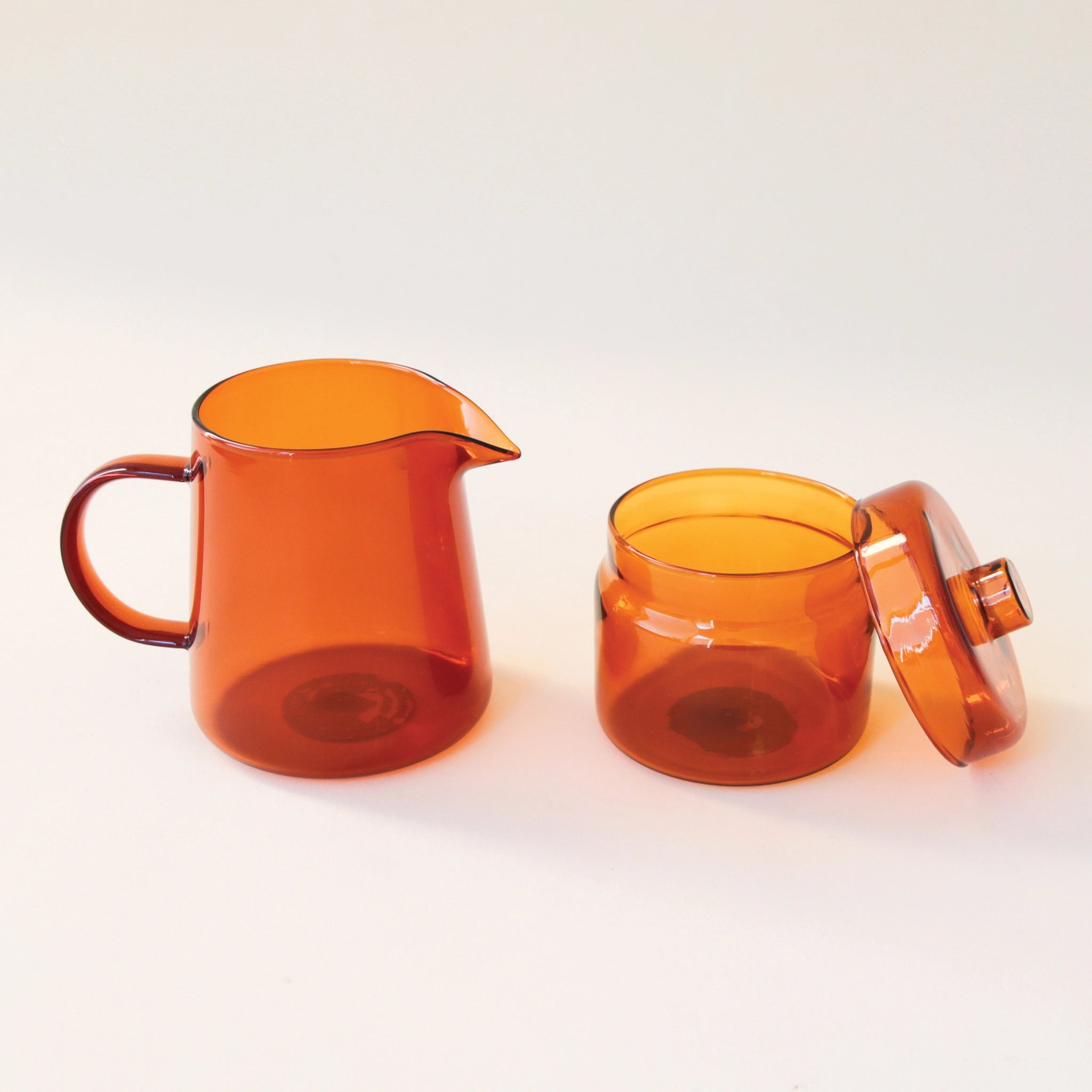 On a white background is an amber glass pitcher and sugar jar. 