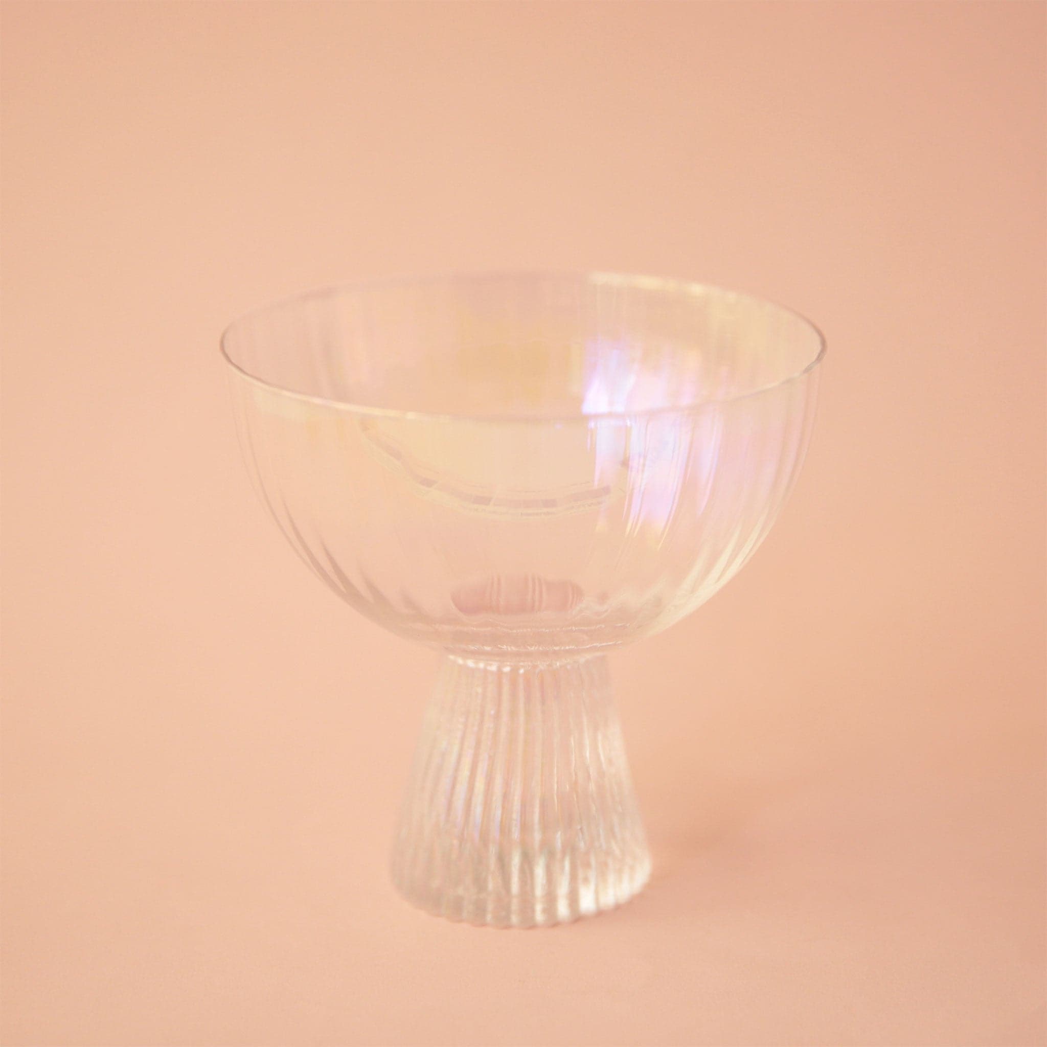 An iridescent coup glass with a ribbed base.