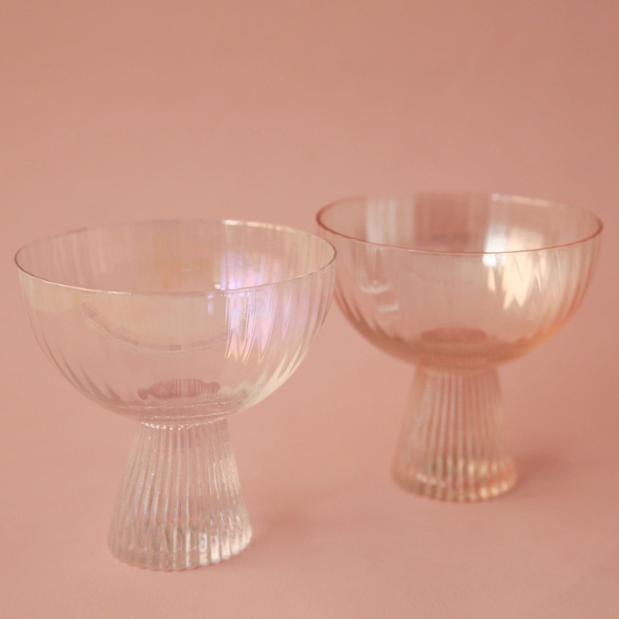 Two iridescent coup glasses with ribbed bases.