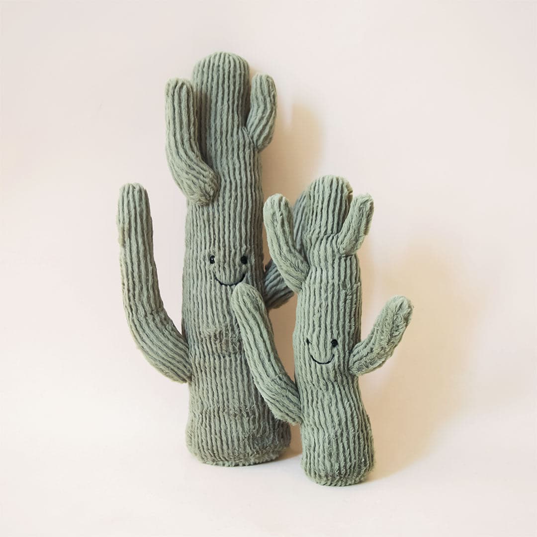 A cactus shaped stuffed animal with a smiling face, photographed here in two different sizes.