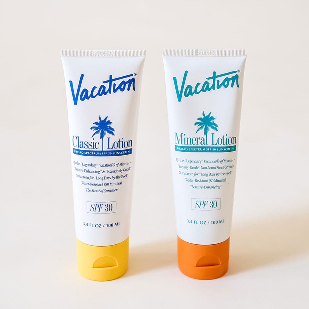 On a white background is a white squeeze tube of sunscreen with a yellow lid and a blue text that reads, &quot;Vacation Classic Lotion SPF 30&quot; along with a blue palm design in the center and photographed next to the mineral sunscreen that has an orange lid. 
