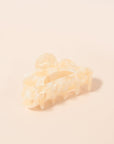 An ivory claw clip with a scalloped edge detail and an ivory and white color.