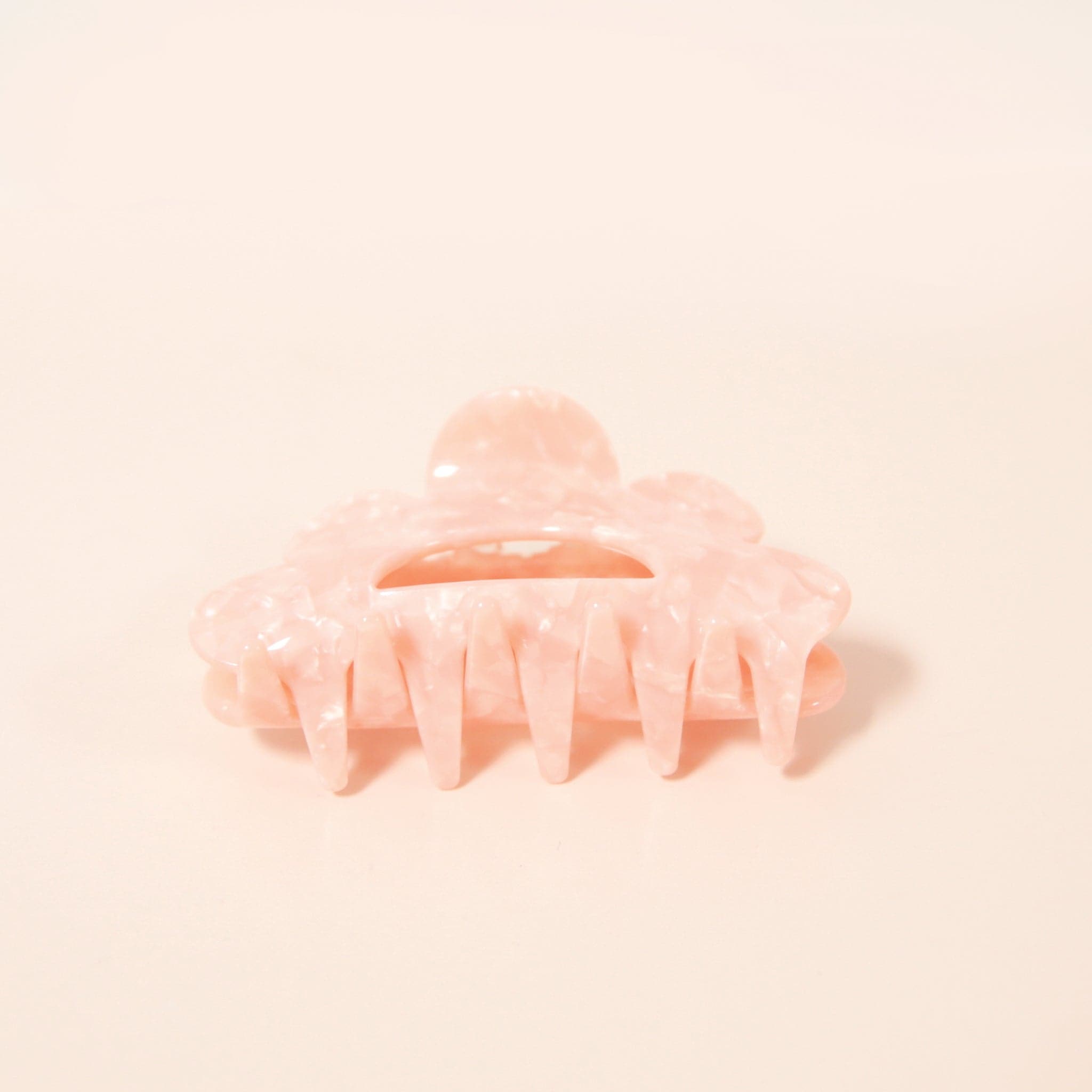 A scalloped peach hair clip made of durable plastic.