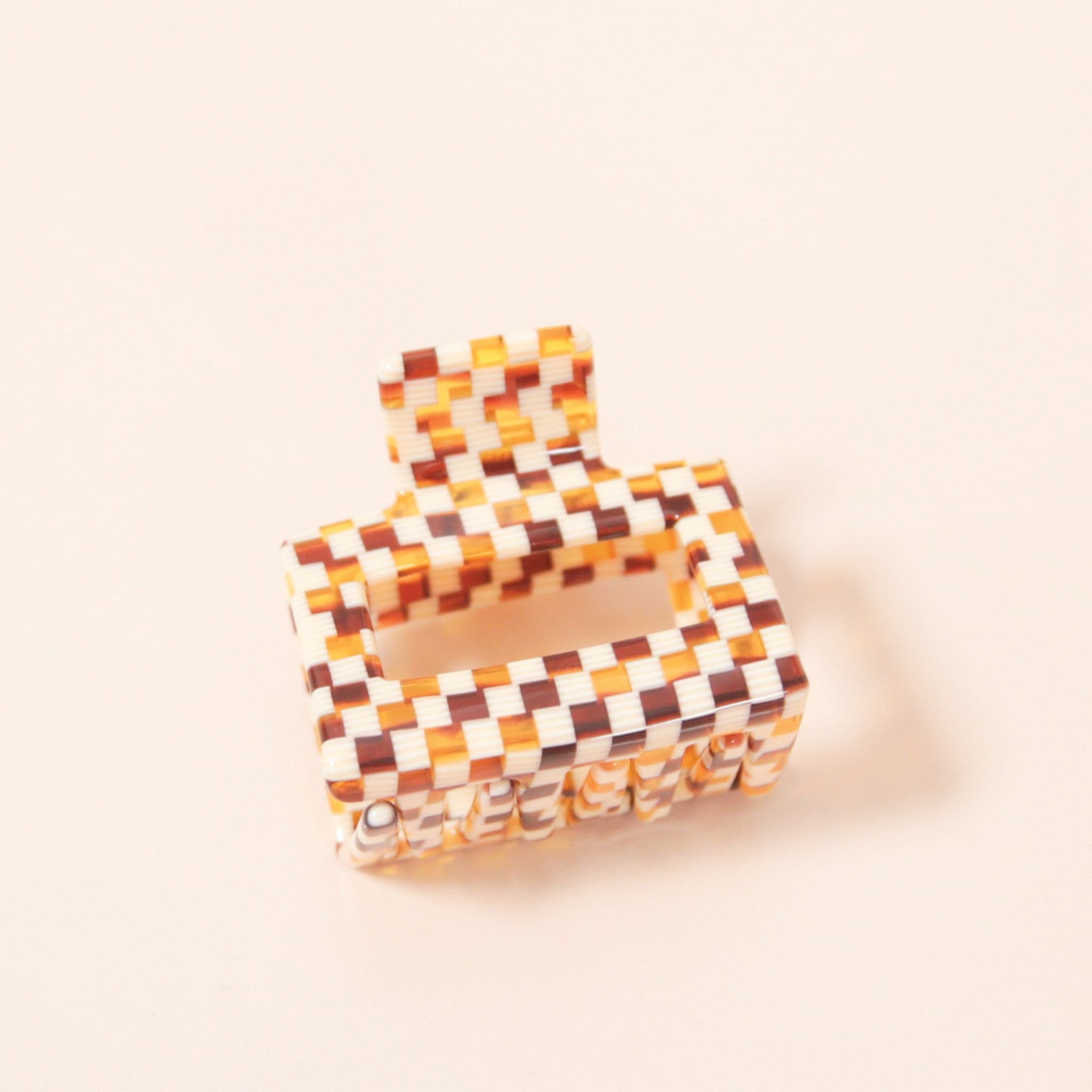 A white and brown acrylic checkered claw hair clip with a square shape and two simple geometric cutouts.