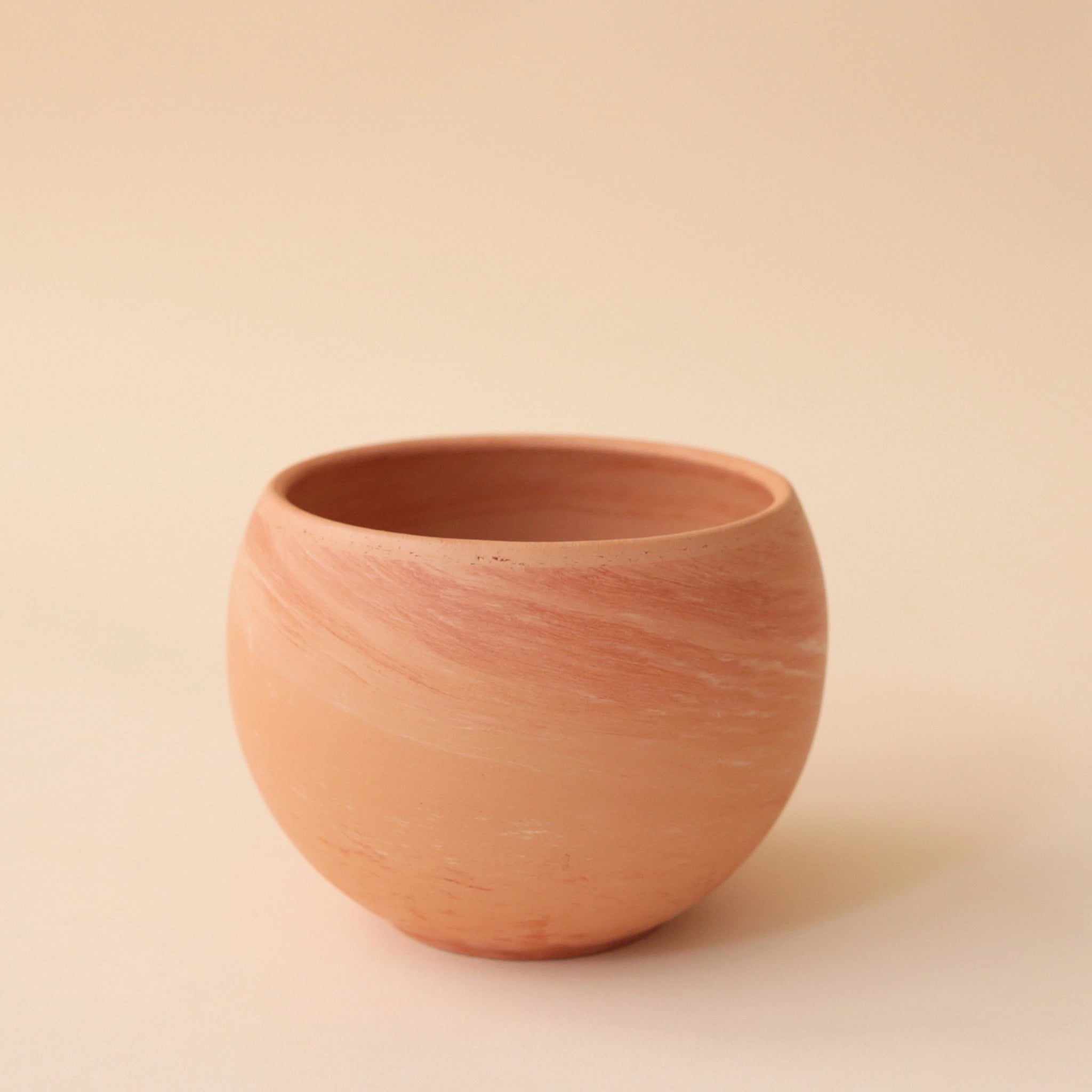On a peach background is a terracotta circle planter.
