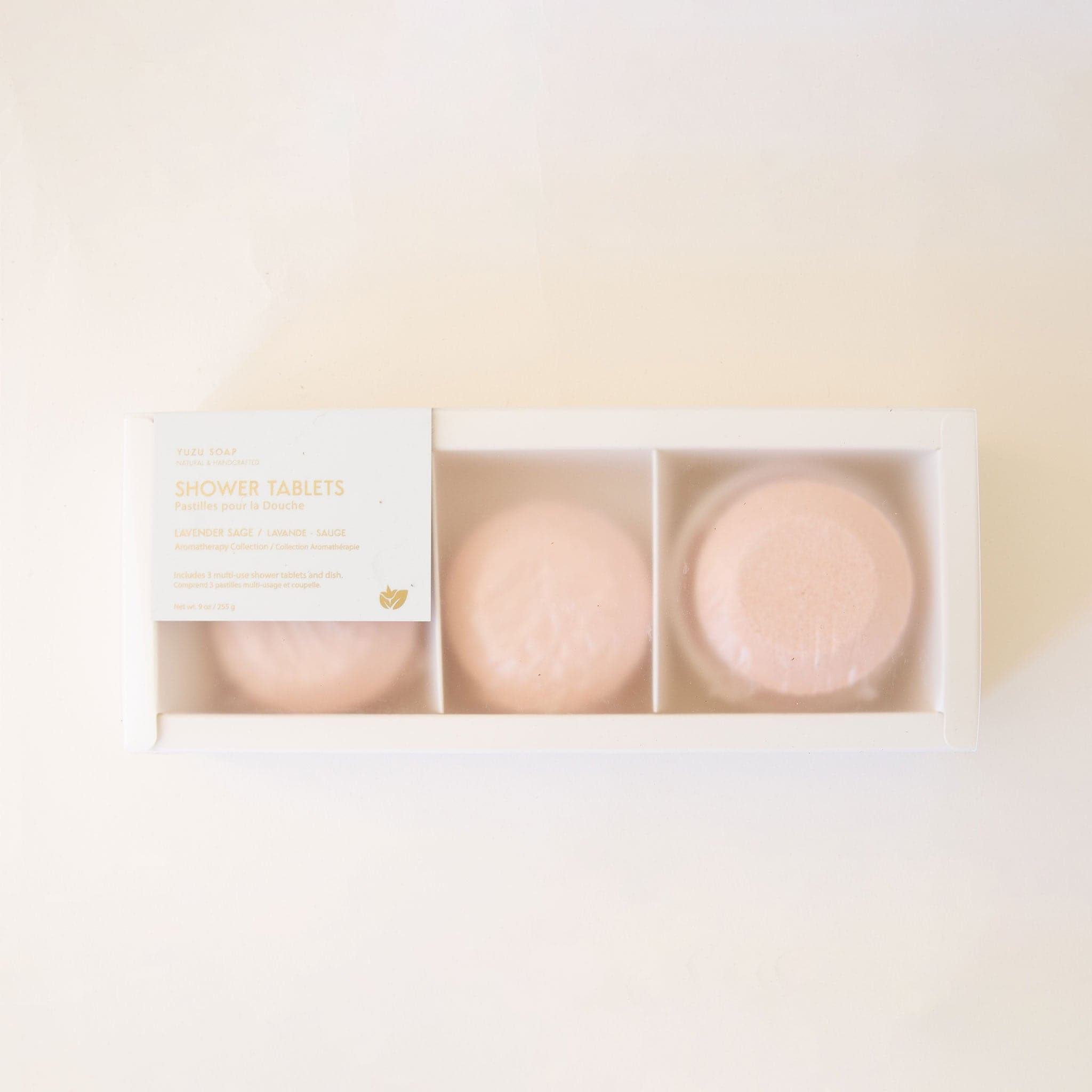 Three soft blush toned shower tablet positioned horizontally in a rectangular white package that reads &#39;Shower Tablets - Lavender Sage&#39; in gold foil. 