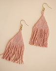 Two blush pink glass beaded earrings with a triangle shape along with fringe detailing on the bottom.