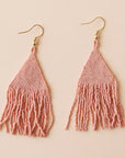 Two blush pink glass beaded earrings with a triangle shape along with fringe detailing on the bottom.
