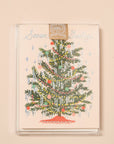 A cream colored card sits against a light peach background. On the front of the card there is a drawing of a dark green Christmas tree. There are yellow and red Christmas lights up and down the tree. There are green, red and pink ornaments spread out all over the tree. Silver tinsel is hanging on the end of each tree branch. At the bottom is a red tree skirt. At the top is a sliver star. Above the tree in silver script it reads ‘season's greetings.’ The card is accompanied by a white envelope.