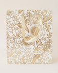 A gold foiled gift bag with metallic cotton handles and a to and from tag.