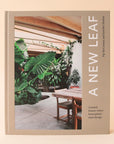 A neutral tan book cover with a photograph of a home with tons of greenery along with sideways white text that reads, "A New Leaf Curated homes where houseplants meet design".