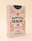 A light pink book cover with pink, lavender and orange foliage and sun and moon graphics along with black text that reads, "Modern Day Magic 8 Simple Rules Realize Your Power and Shape Your Life".