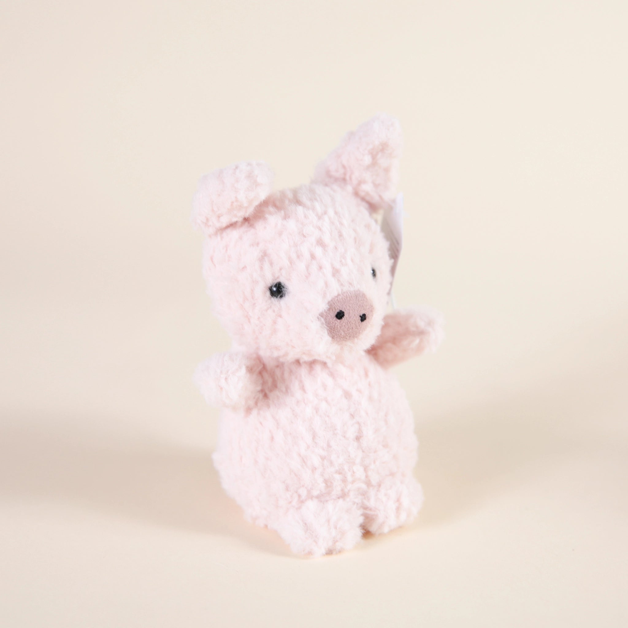 A fuzzy light pink pig stuffed animal that is sitting upright.
