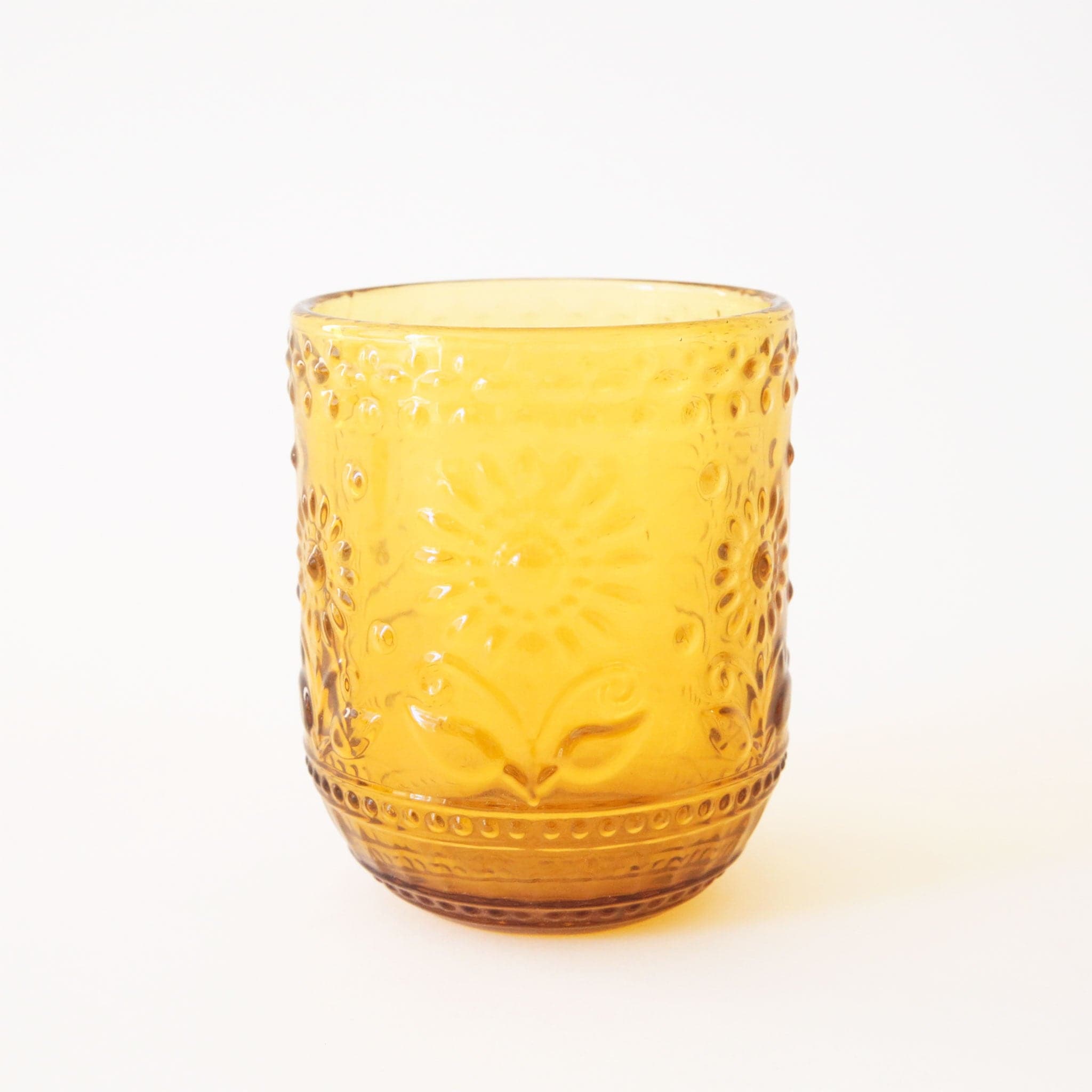 Embossed yellow drinking glass with raised floral detailing.