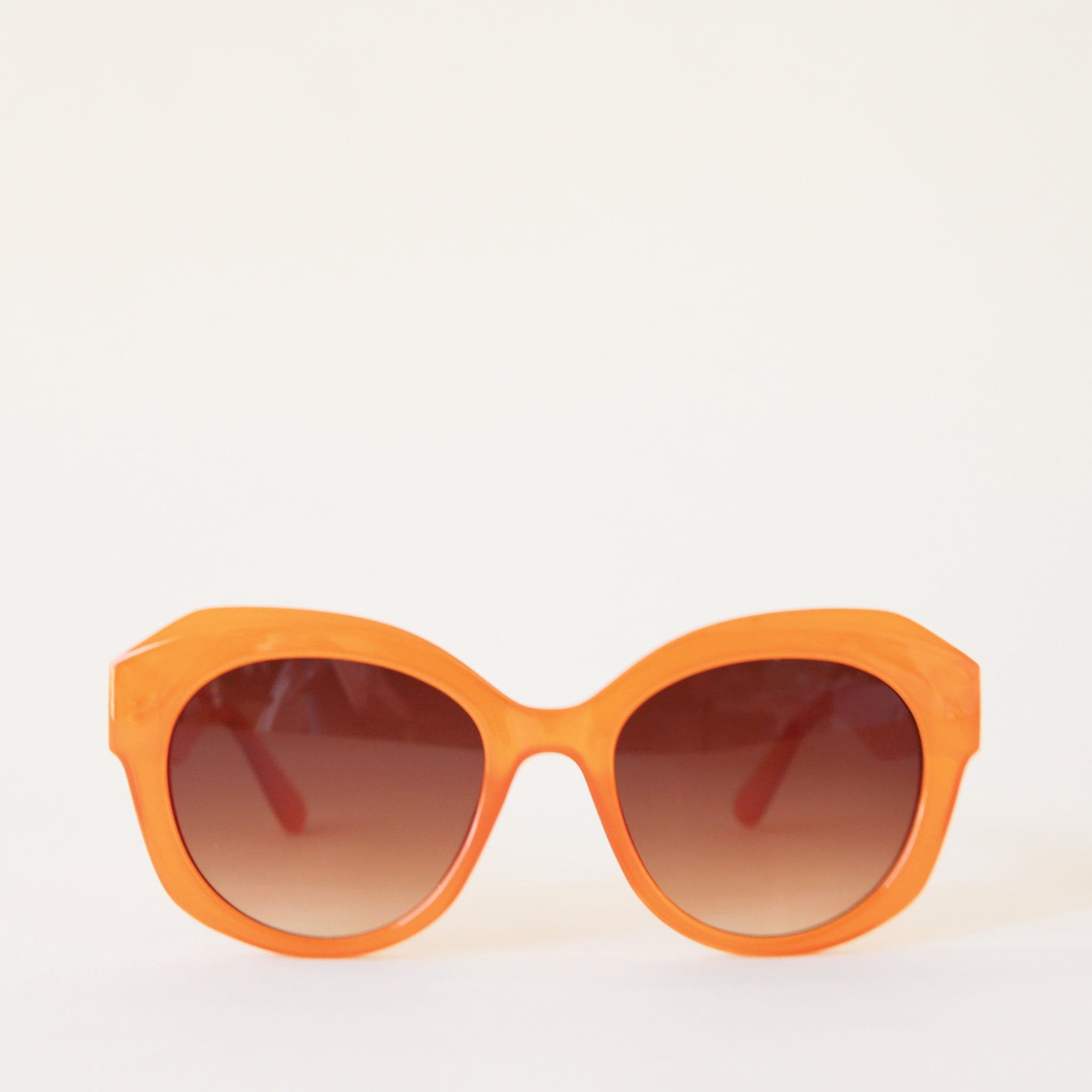 Chunky round orange sunglasses with a brown lens.