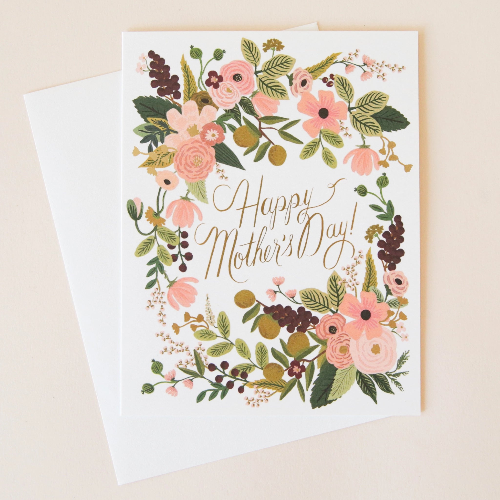 On a cream background is a white card with a pink and green floral design around the edges and text in the center that reads, "Happy Mother's Day!" along with a white envelope.