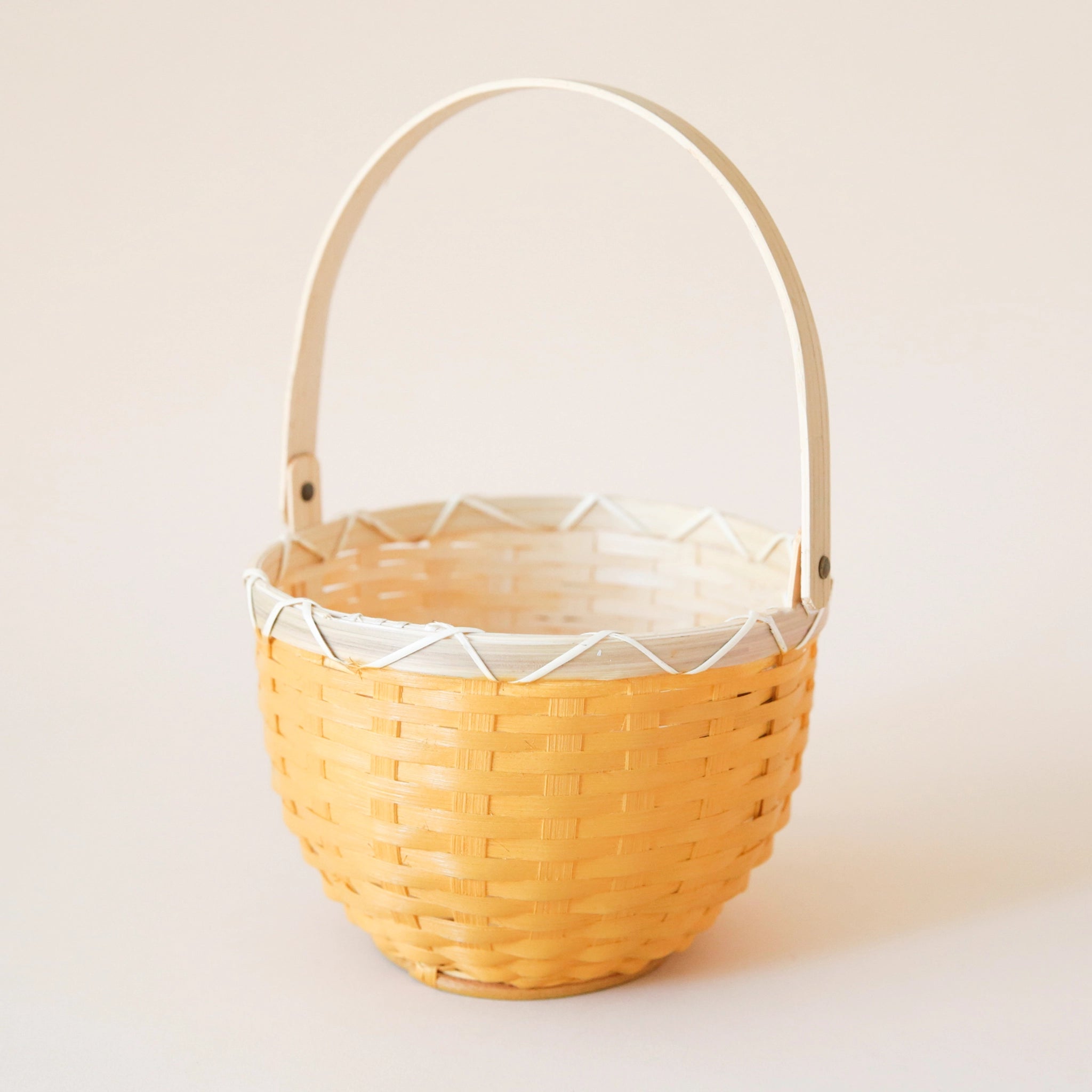 On a cream background is a yellow and cream woven rattan Easter basket. 