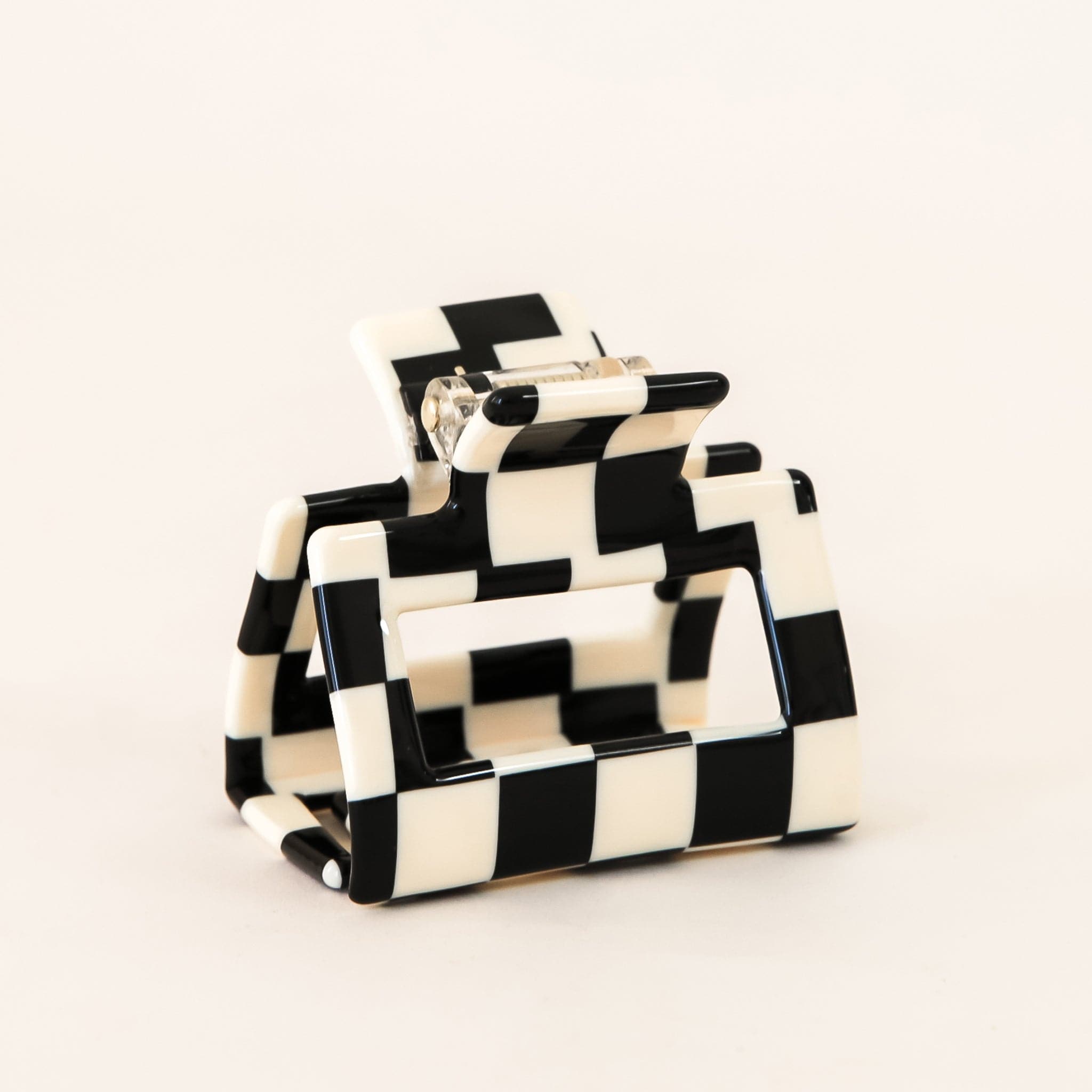 Small black and white checkered claw hair clip with a square shape and two simple geometric cutouts.