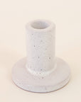 Against a white background is a gray, ceramic candle holder with black speckles on it. The base is round with a tall, cylinder top.