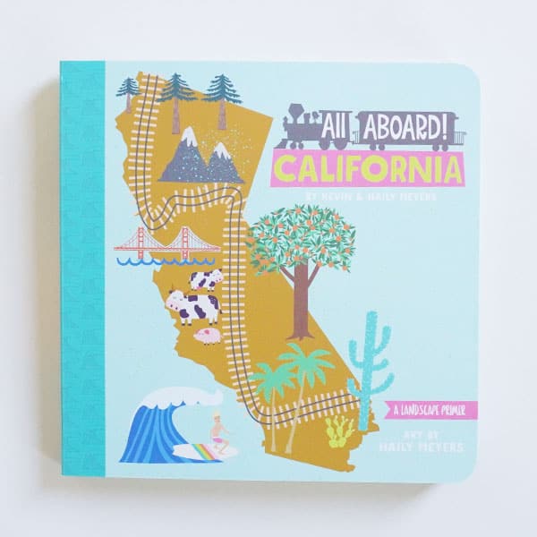 A small children&#39;s book titled &quot;All Aboard California. Art by Haily Meyers.&quot; Illustration shows the state of California, a railroad track going from one end to another, trees, mountains, cows, Golden Gate Bridge, palm trees, orange tree, and a surfer.