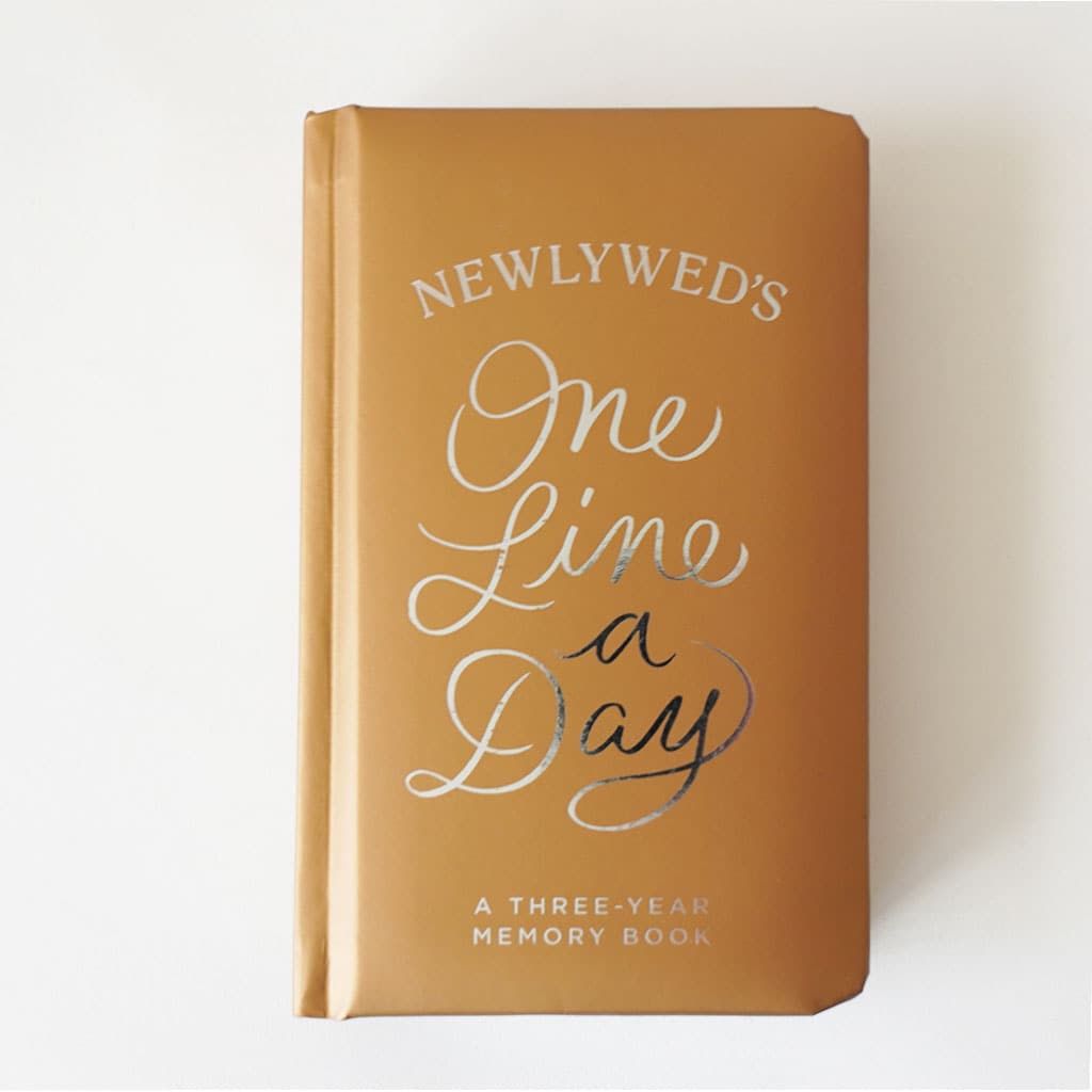 High quality, honey toned memory book reading &#39;Newlywed&#39;s one line a day; a three year memory book&#39; in silver foil lettering across the padded cover. 