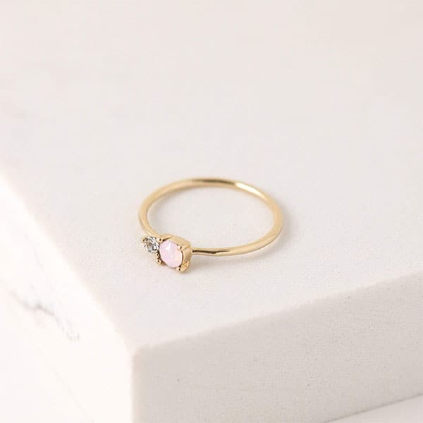 A thin gold band ring with a circle pink opal accented with a smaller Swarovski Crystal right besides it. 