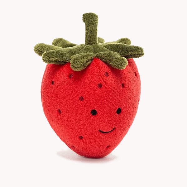 On a white background is a red strawberry stuffed animal with a green leafy top and a smiling face. 