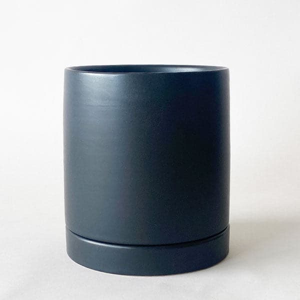 On a white background is a black ceramic planter with a removable tray for watering.