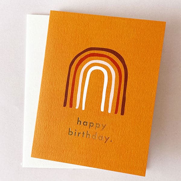 Orange greeting card with burgundy, red, tan and white rainbow with "happy birthday" in gold foil and white envelope.