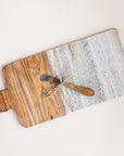 On a cream background is a wood and grey marble cutting board with a coordinating butter knife.