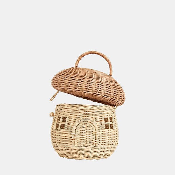 A natural colored rattan mushroom house basket with a handle on the top, a little arched door and square windows.