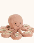 A pink octopus stuffed animal with a smiling face, photographed on a cream background.