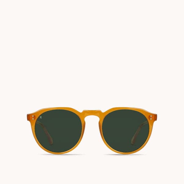 In front of a white background is a pair of round, orange sunglasses with green lenses. 