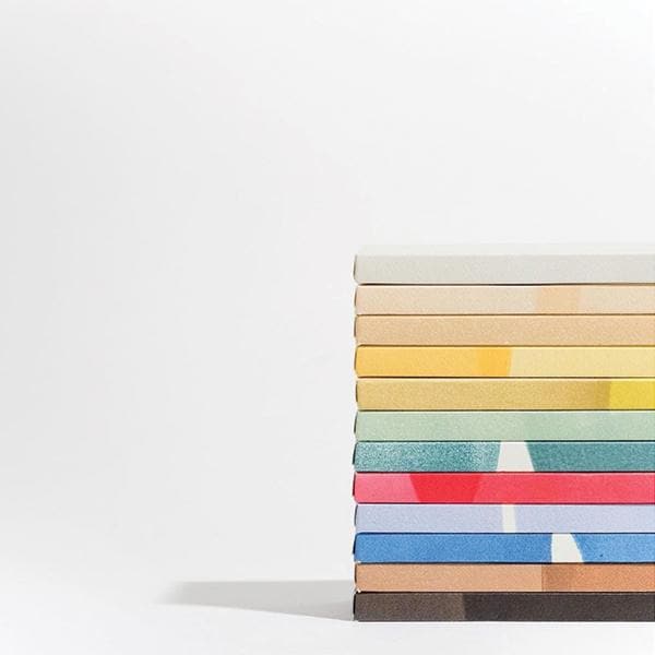 A photograph of all the options available from Mast Chocolate stacked on one another. They all have different colored packaging ranging from cream to yellow to green, red, blues and black.