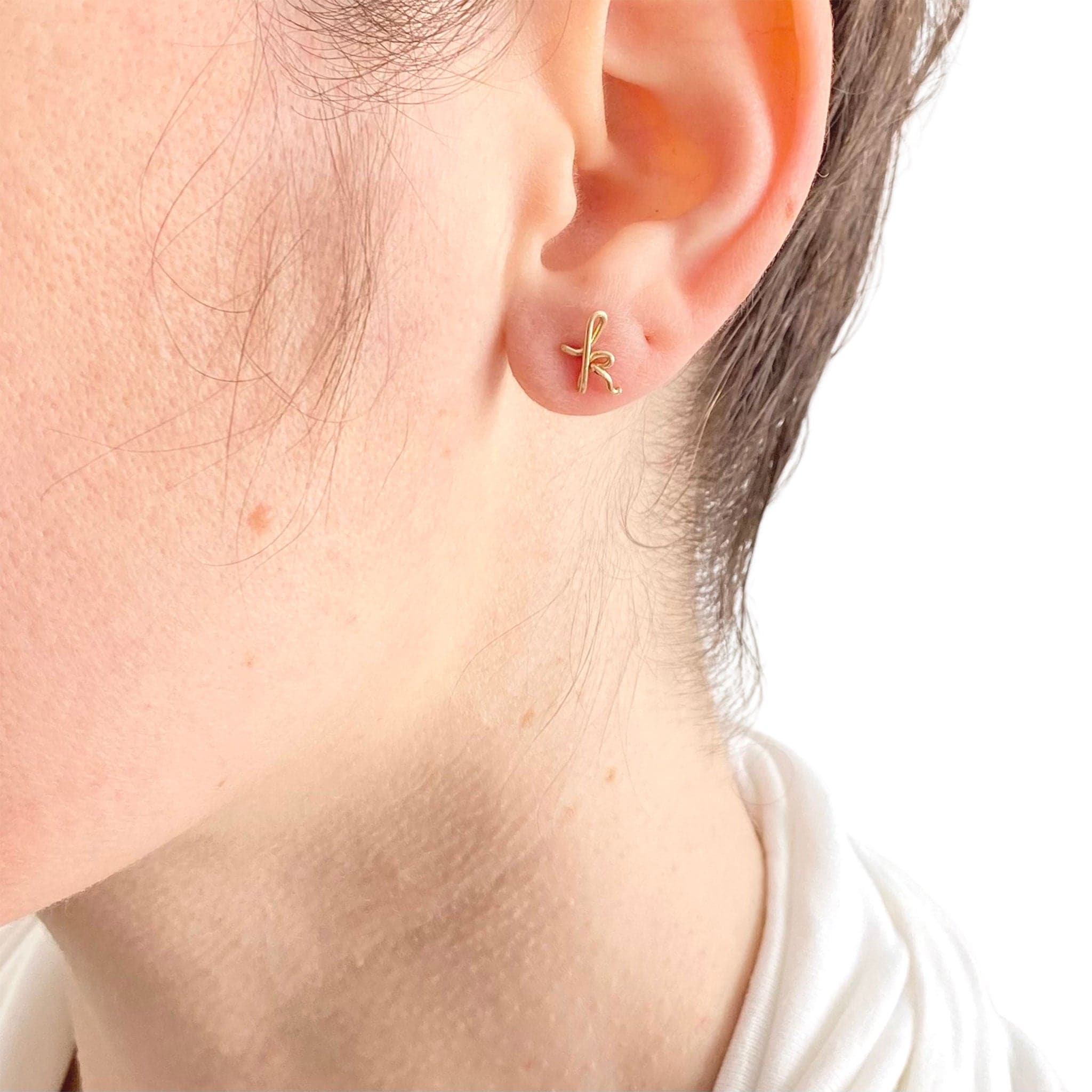 A model wearing the 14k gold filled &#39;k&#39; shaped earring. 