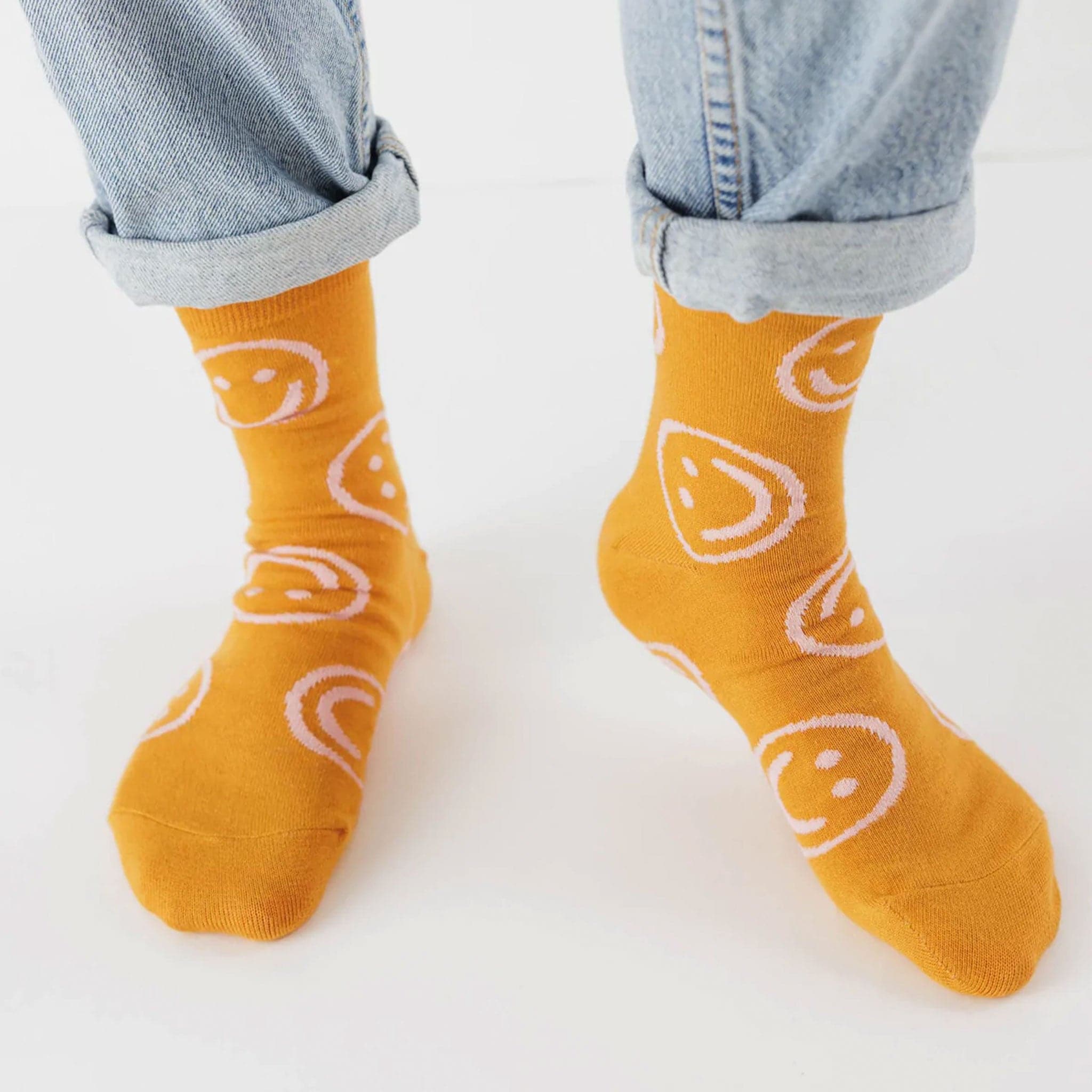 A yellow pair of socks with smiley face designs.